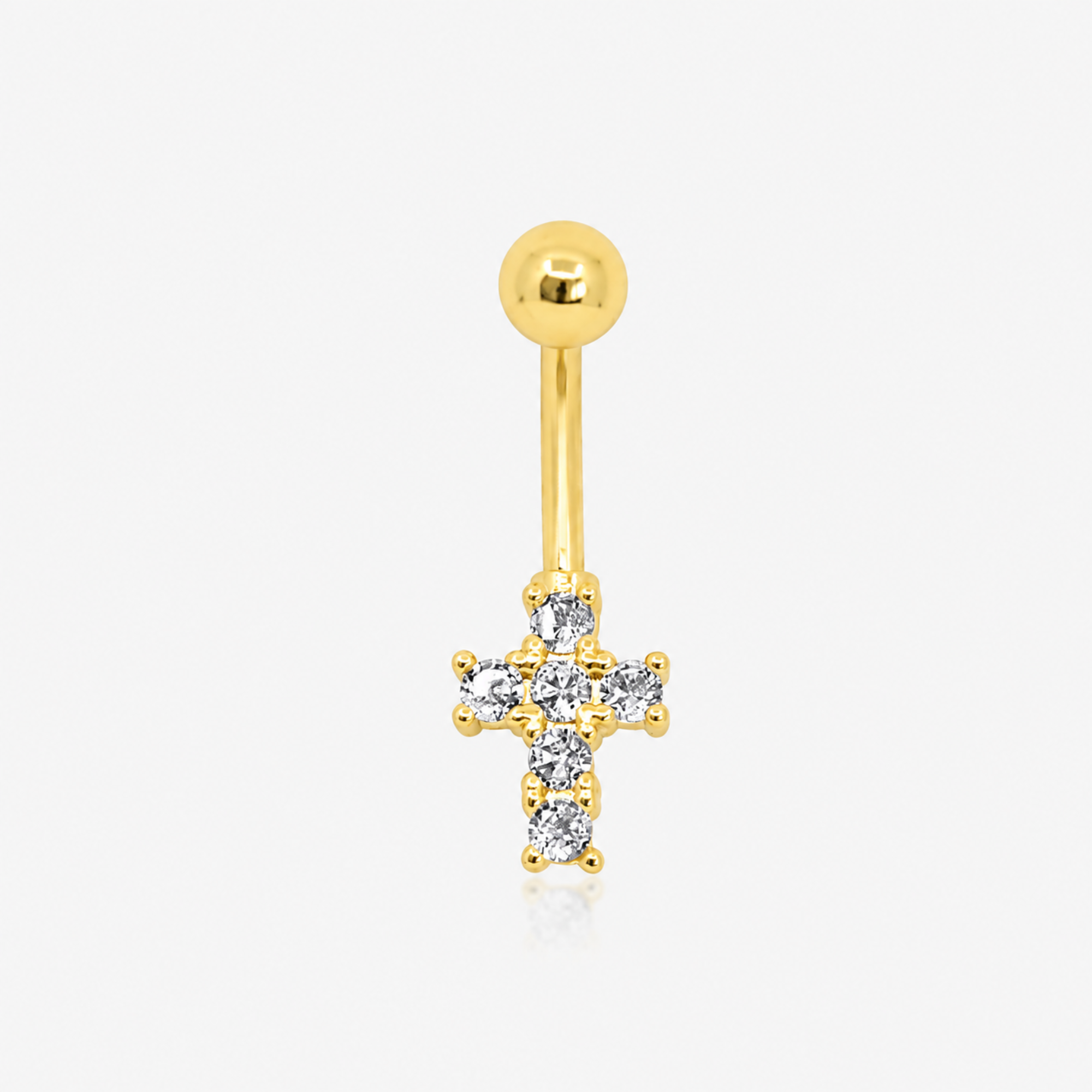 Gold tone curved belly ring with a round top ball and a clear stone cross charm on a white background