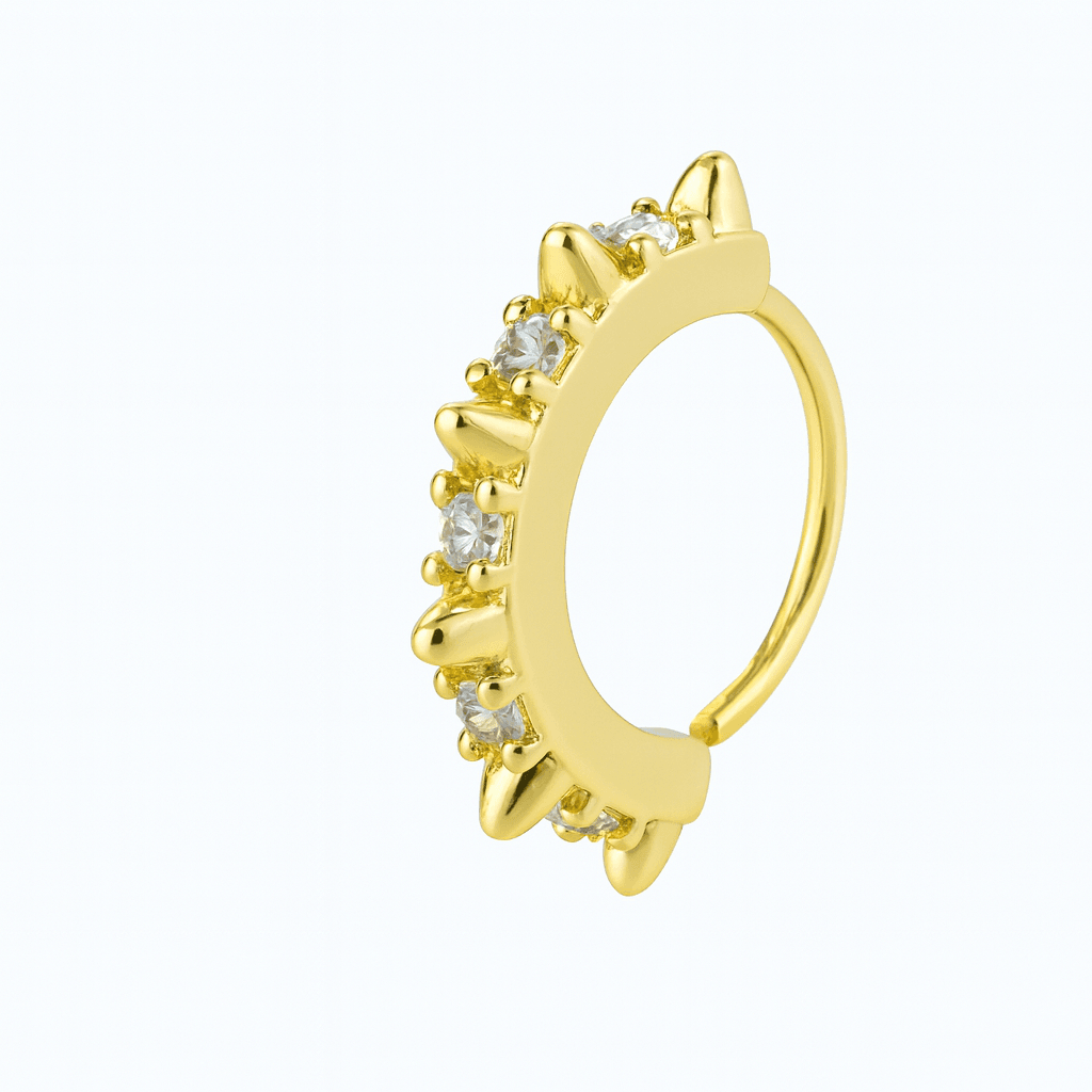 Gold tone nose hoop lined with clear stones and small spike accents on a white background