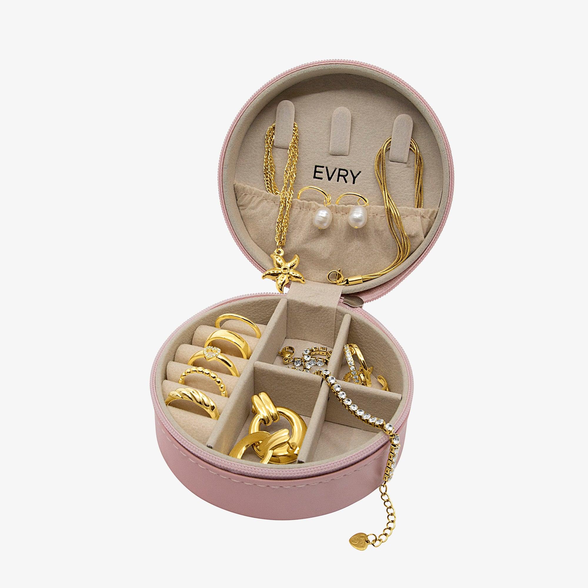 Open round pink jewelry case holding gold tone rings, earrings and necklaces